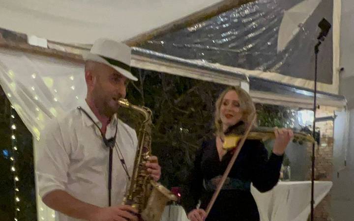 כנריות לחתונה – כנרית וסקסופוניסט מנגנים מתחת לאוהל בחתונה