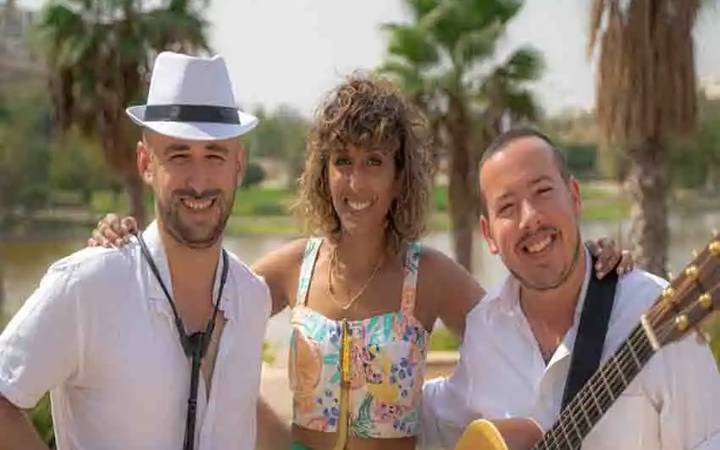 איך בוחרים נגנים לאירוע – סקסופוניסט, זמרת וגיטריסט מחייכים באירוע חוץ בין עצי דקל