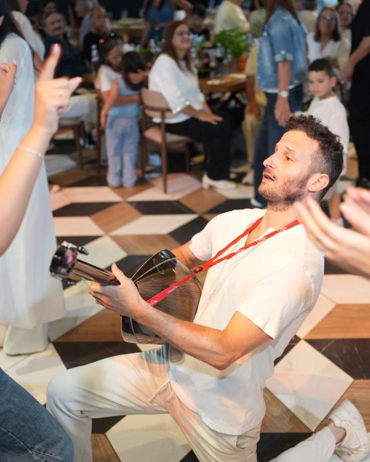 Bouzouki player for weddings – Ofer kneels and plays for the guests on the dance floor