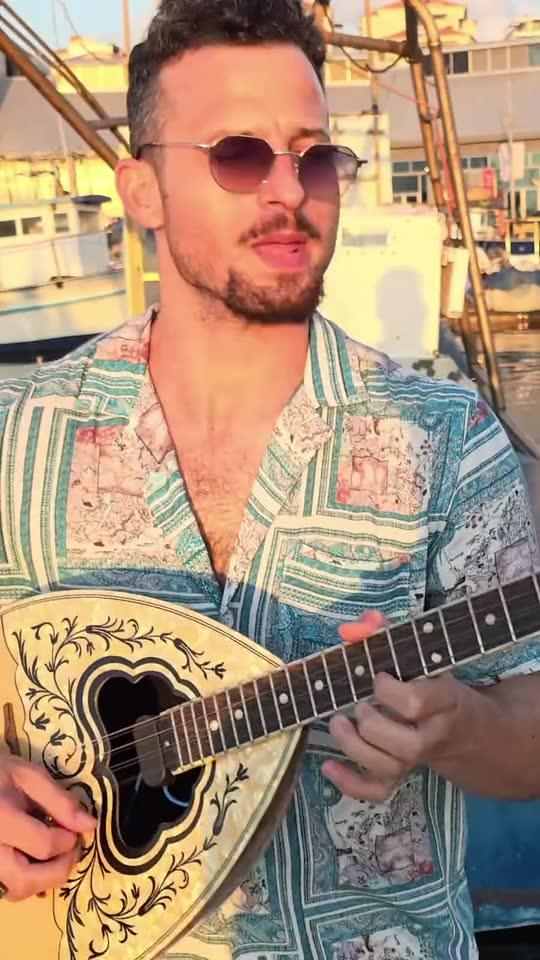 Bouzouki player for events in Israel – Ofer plays the bouzouki and smiles at sunset by the boats in the harbour