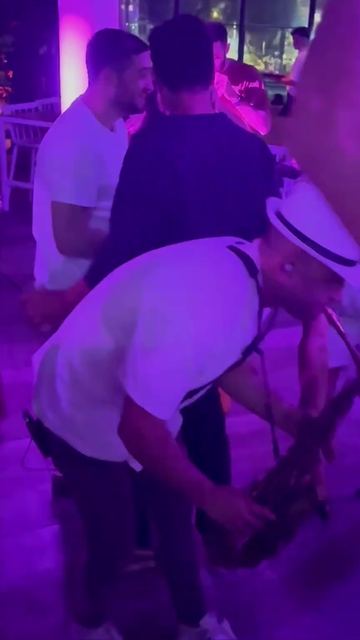 סקסופון טירוף ברחבה – נגן סקסופון מתכופף עם הסקסופון בין האורחים