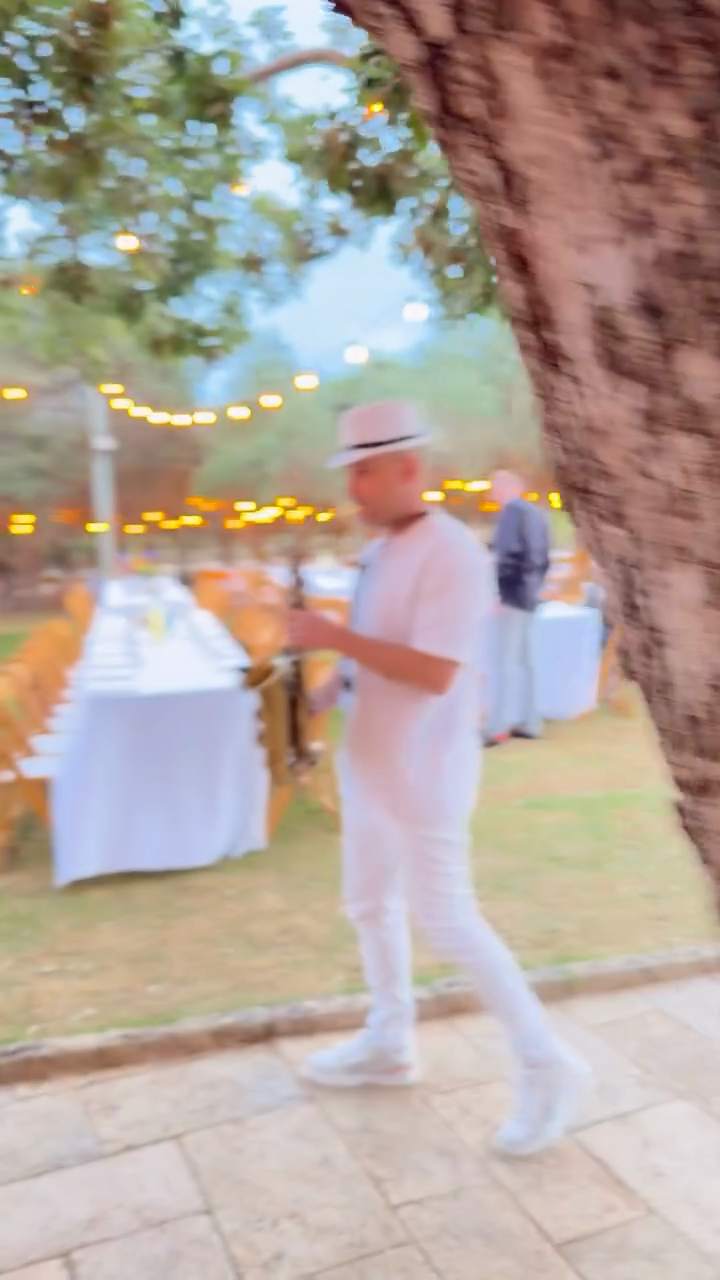 סקסופון לחתונה – טל רודובסקי מנגן בסקסופון בין שולחנות קבלת הפנים בגן אירועים תחת שרשראות אורות