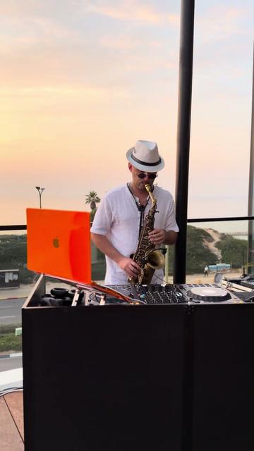 DJ avec saxophone live – un saxophoniste à côté de la cabine du DJ au coucher du soleil