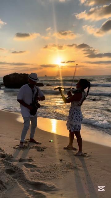 Violon et saxophone pour événements – une violoniste et un saxophoniste au coucher du soleil sur la plage