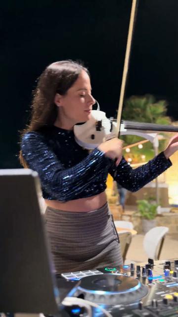 Techno saxophone et violon – une violoniste joue à côté de la cabine du DJ