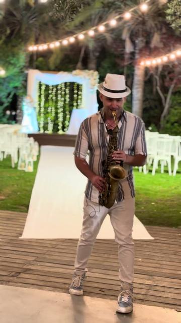 Saxophone pour le cocktail de mariage – un saxophoniste dans un jardin de réception près de la houppa