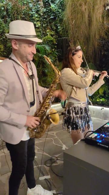 כנרת וסקסופון Live on DJ – סקסופוניסט וכנרית מנגנים ליד עמדת הדי-ג'יי